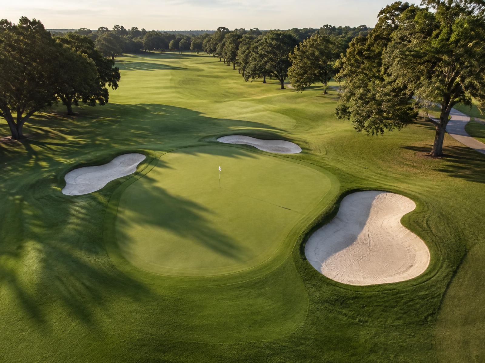 Aerial view of a renovated golf green framed by new sand bunkers